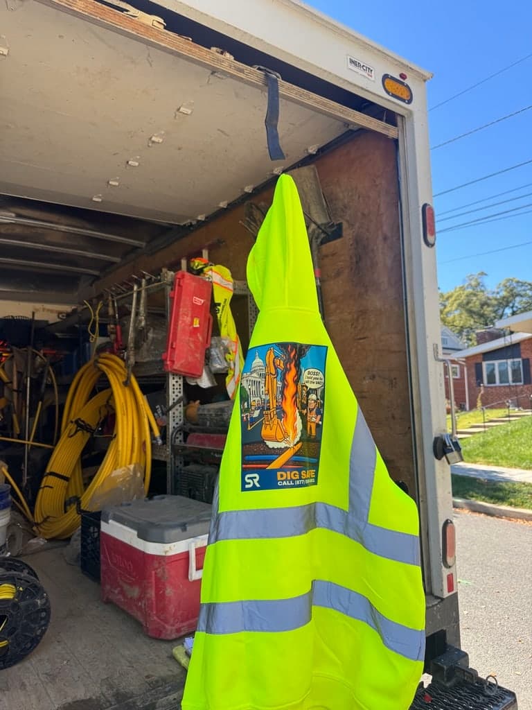 Close-up of the Dig Safe artwork on a hi-vis hoodie at the truck tailgate